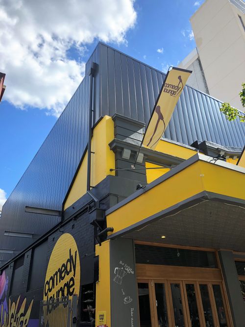 Dark standing seam metal cladding above a yellow-trimmed entrance on an architectural building project