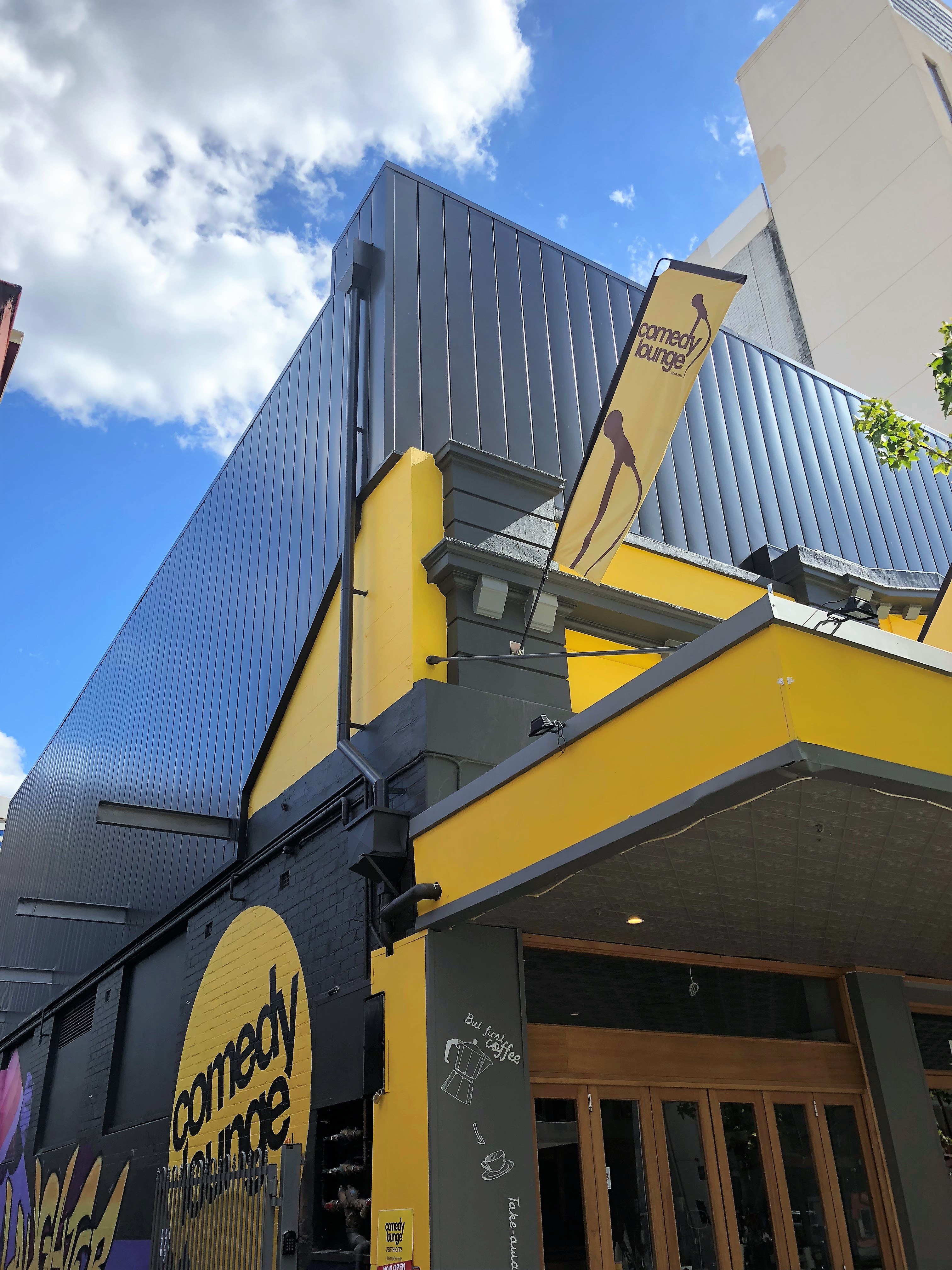 Dark standing seam metal cladding above a yellow-trimmed entrance on an architectural building project