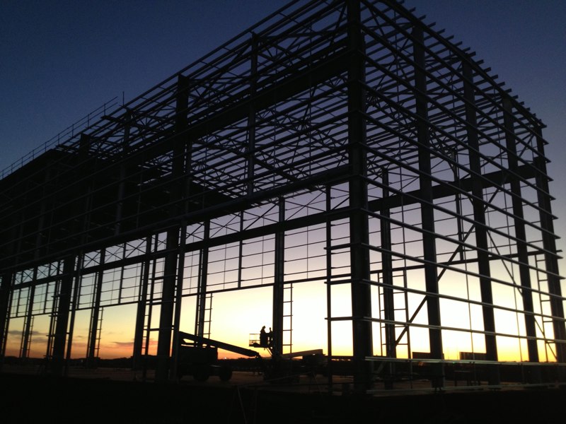 Steel frame of a large building at sunset with a worker on an elevated platform