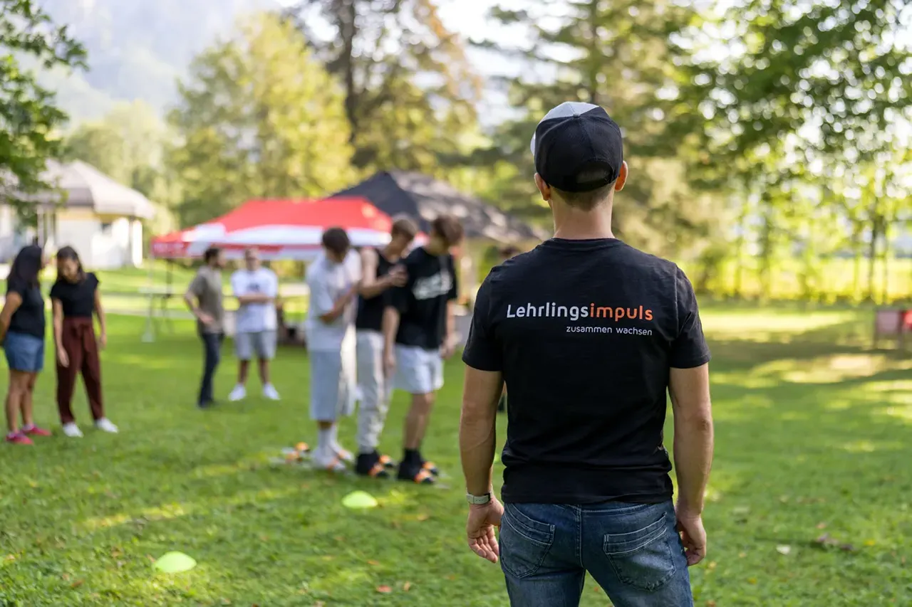 Outdoor Lehrlingstraining mit Jakob als Trainer, welcher im Vordergrund steht und die Gruppenübung leitet.