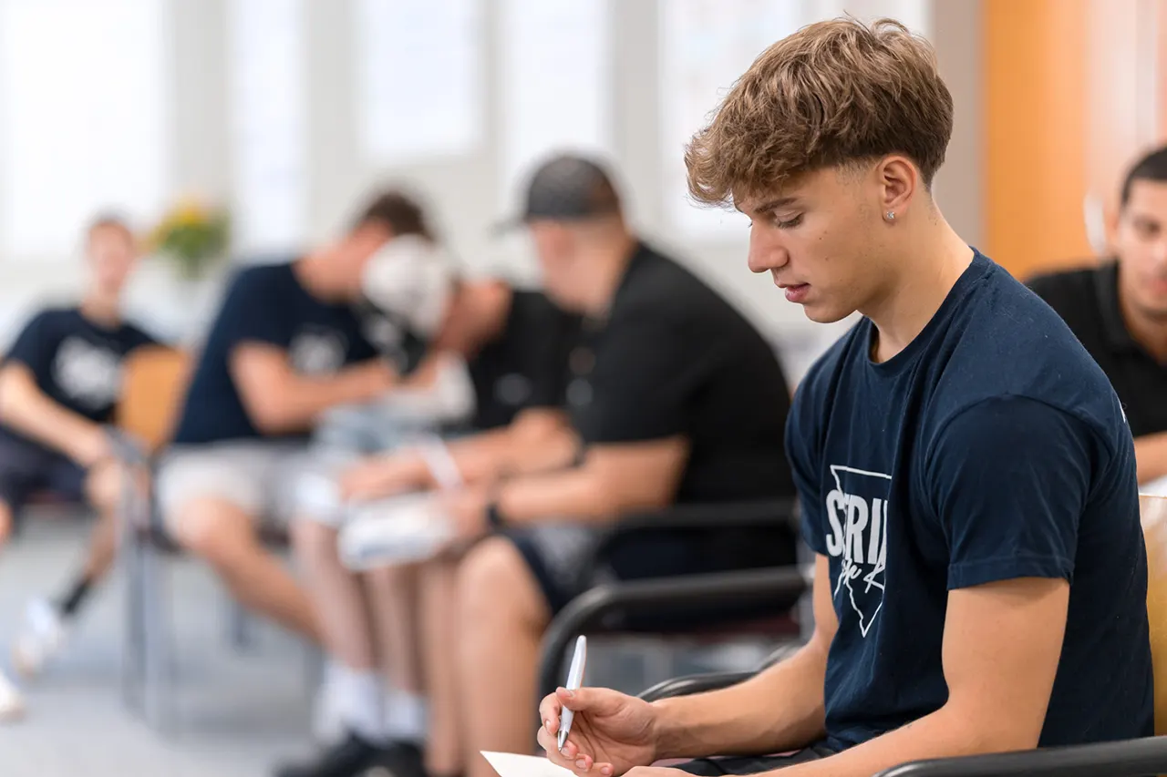 Lehrling beim Schreiben persönlicher Notizen während eines Lehrlingstrainings von Lehrlingsimpuls – individuelle Auseinandersetzung mit Seminarthemen in konzentrierter Atmosphäre.