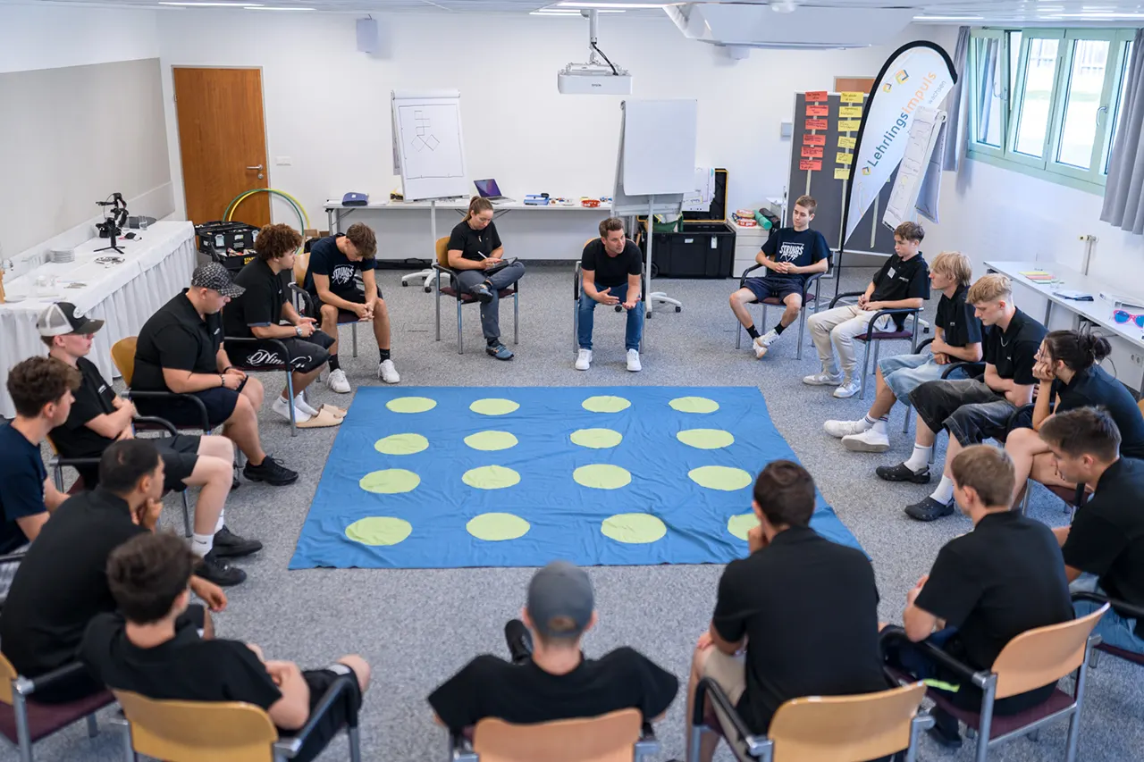 Lehrlinge beim Lehrlingstraining von Lehrlingsimpuls – Gruppenübung im Sitzkreis zur Förderung von Teamentwicklung, Kommunikation und sozialem Lernen im Seminarraum.