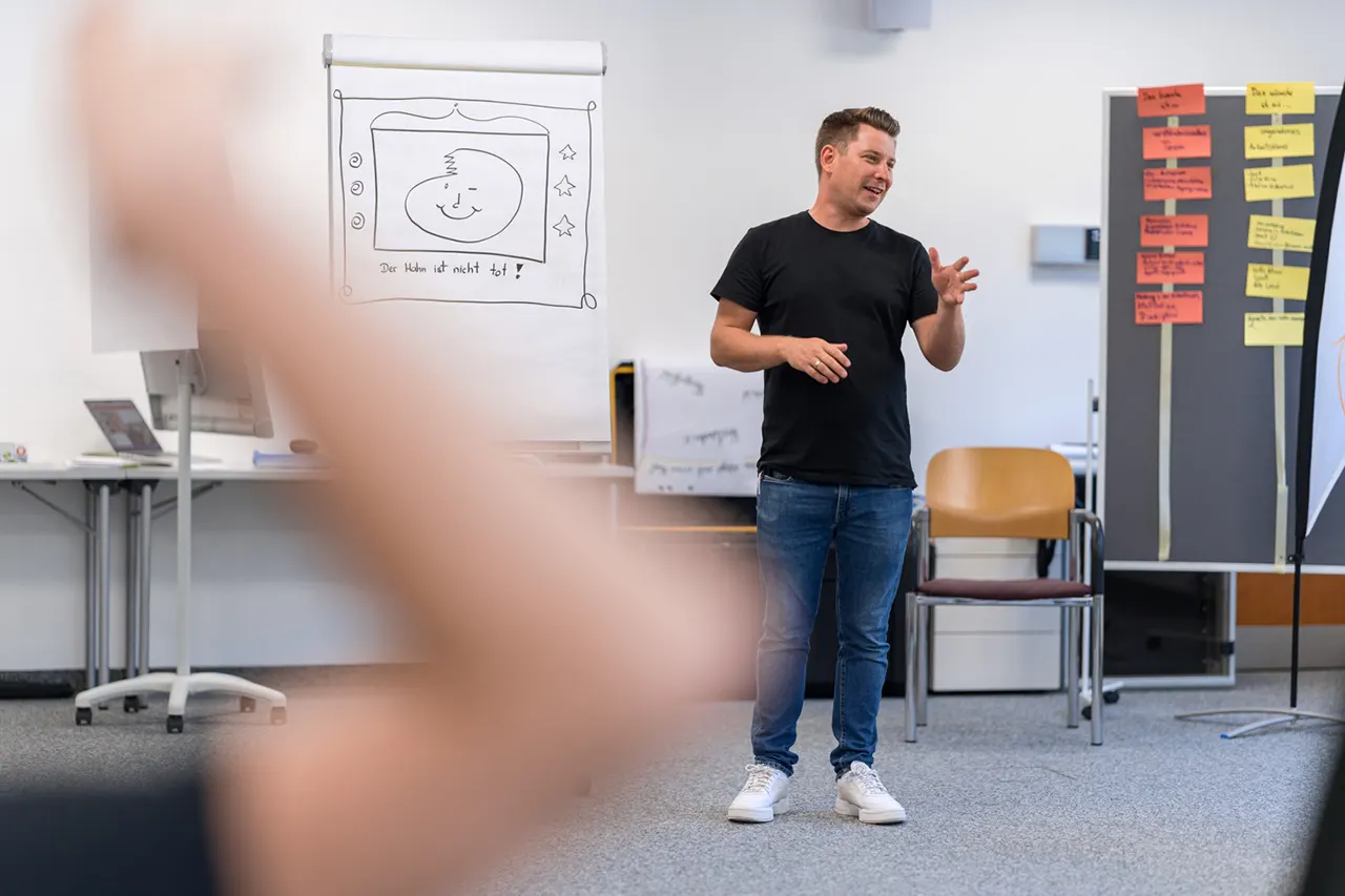 Trainer Simon Schelkshorn von Lehrlingsimpuls bei einem interaktiven Vortrag im Lehrlingsseminar – Visualisierungen und aktive Beteiligung fördern das Verständnis und den Austausch mit Lehrlingen.