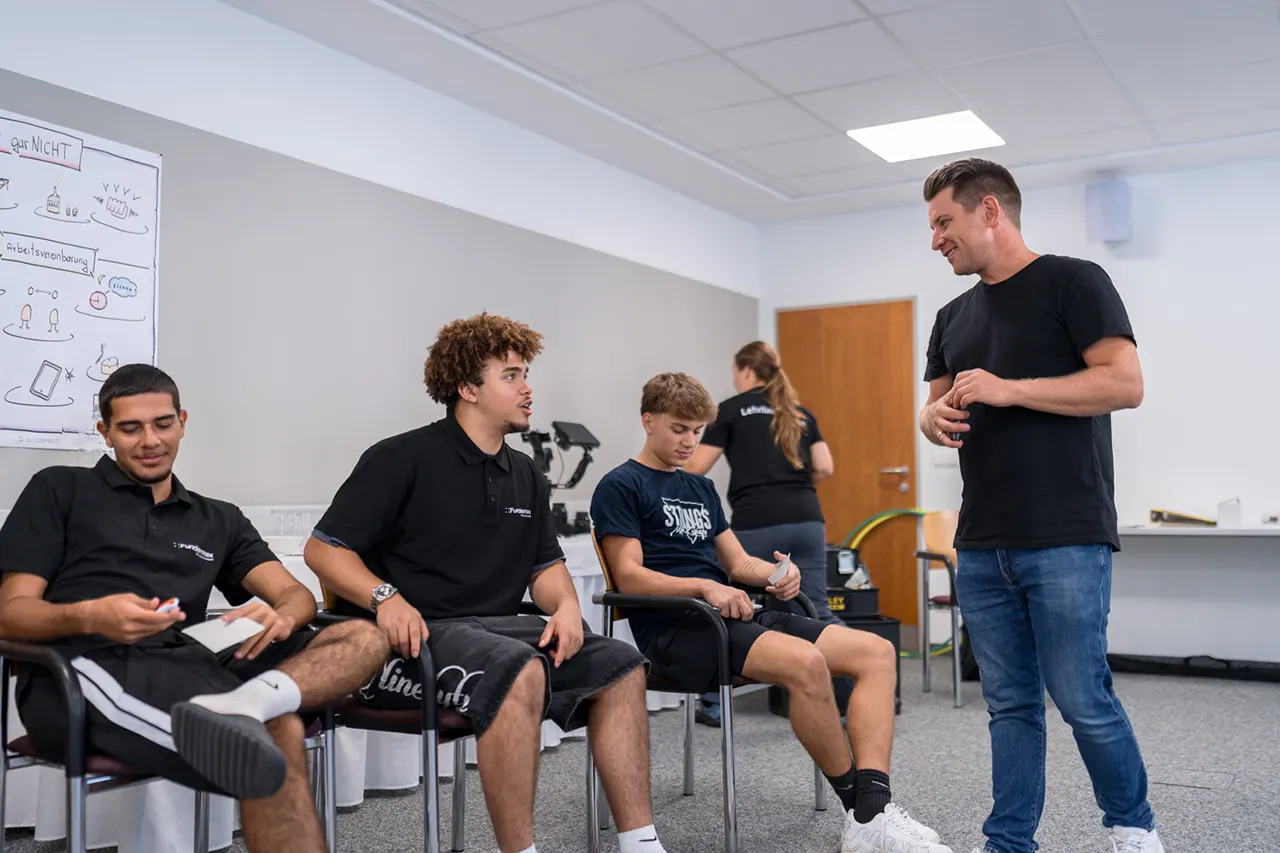Trainer Simon Schelkshorn von Lehrlingsimpuls im persönlichen Austausch mit Lehrlingen während eines Lehrlingsseminars – praxisnahe Interaktion zur Stärkung von Soft Skills und Teamfähigkeit.