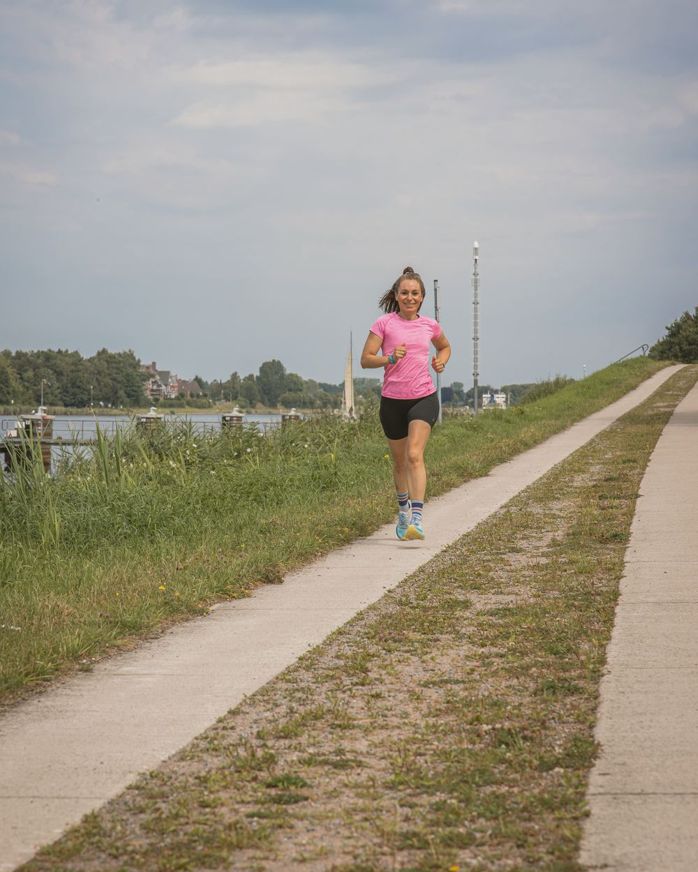 Sabine Pützer läuft auf einem langen Deichweg am Wasser