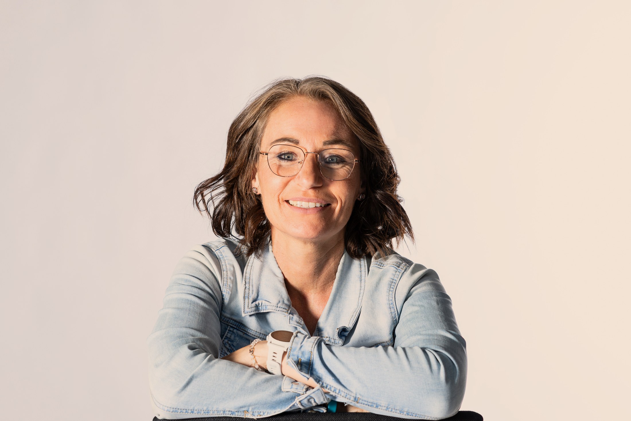 Sabine Pützer lacht, auf einem Stuhl sitzend