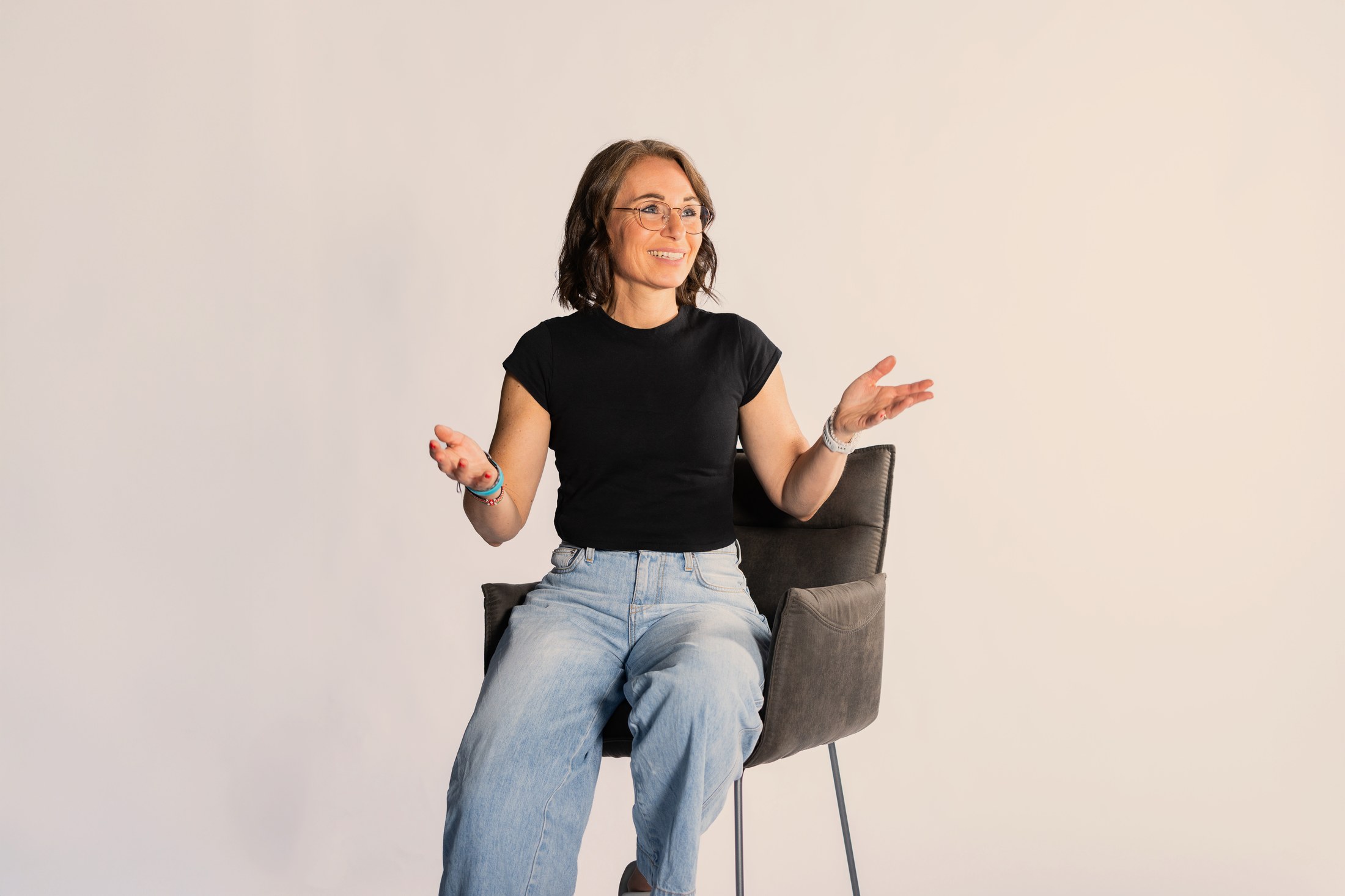 Sabine Pützer lacht, auf einem Stuhl sitzend