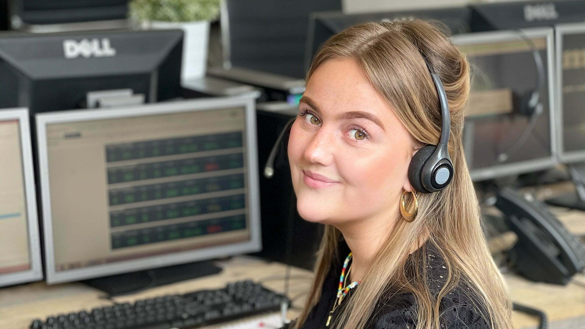 Smiling employee with a headset between monitors in an office