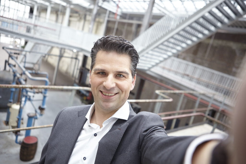 Remco Kraal taking a selfie in an industrial building with stairs and pipes