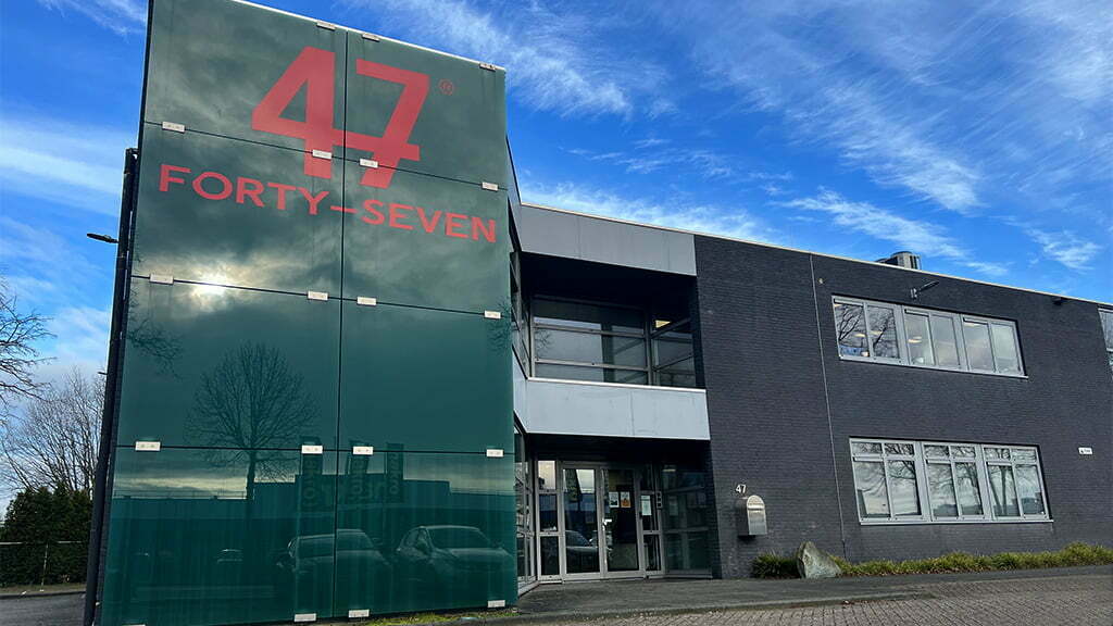 Office building with a green glass facade and the red Forty-Seven logo under a blue sky