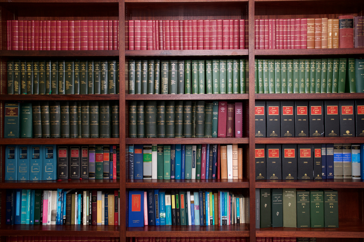 Wooden bookcase full of legal reference works in red, green and blue bindings
