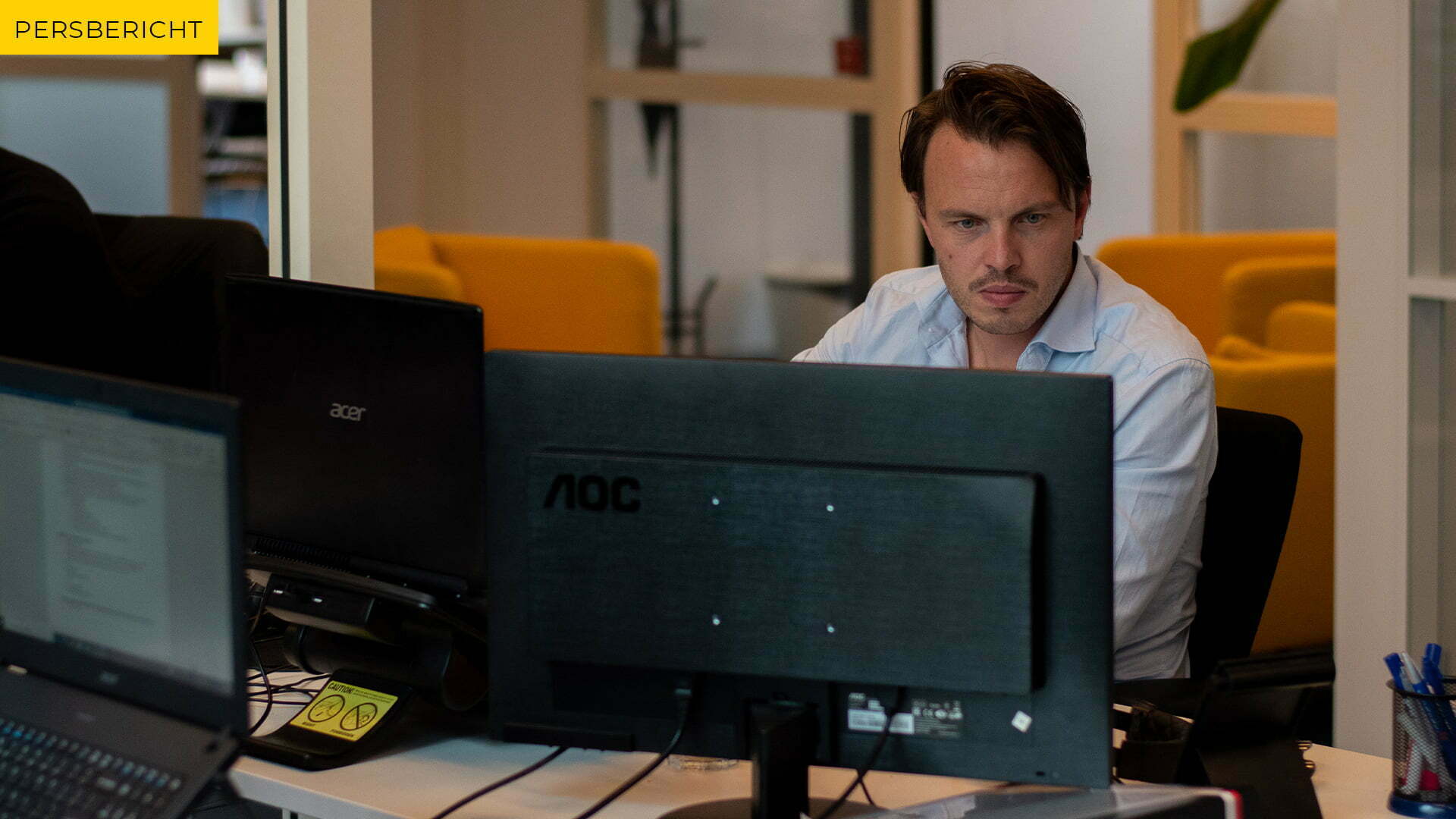 Man behind a screen in an office, with the label Press release in the top left