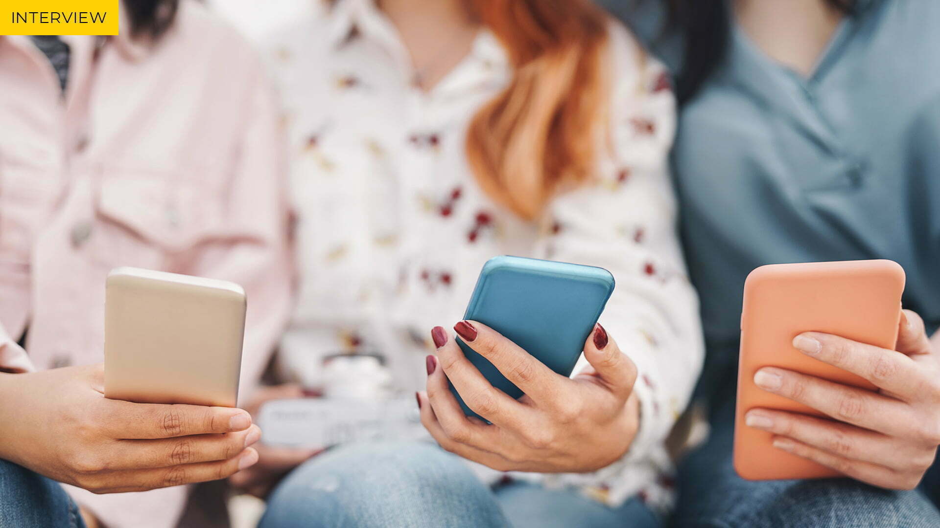 Three young people each holding a smartphone, with the label Interview in the top left