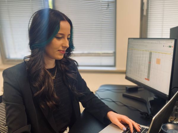 Recruiter behind a laptop with a spreadsheet on the screen, smiling at the screen
