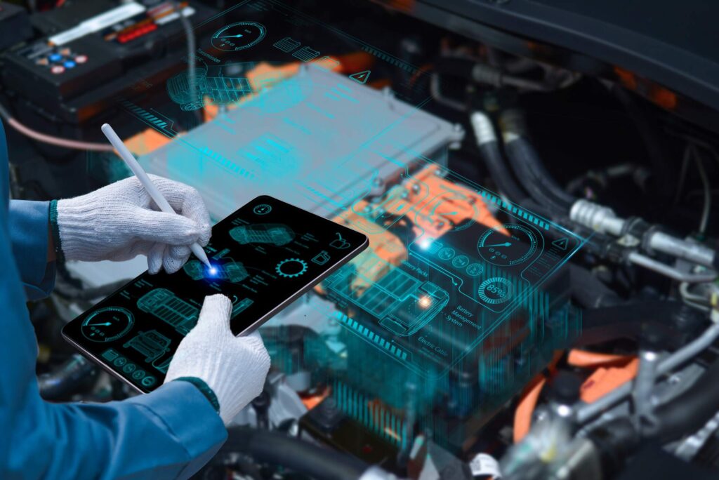 Hands in work gloves operating a tablet showing diagnostics above a car engine