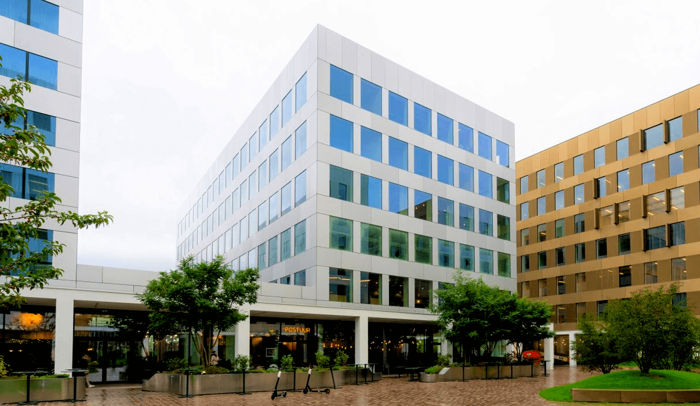 Office building with a glass facade and green trees on a square