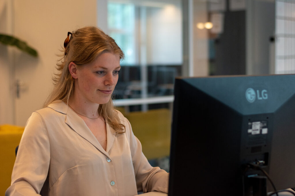 Woman with blonde hair concentrating behind a computer screen in an office