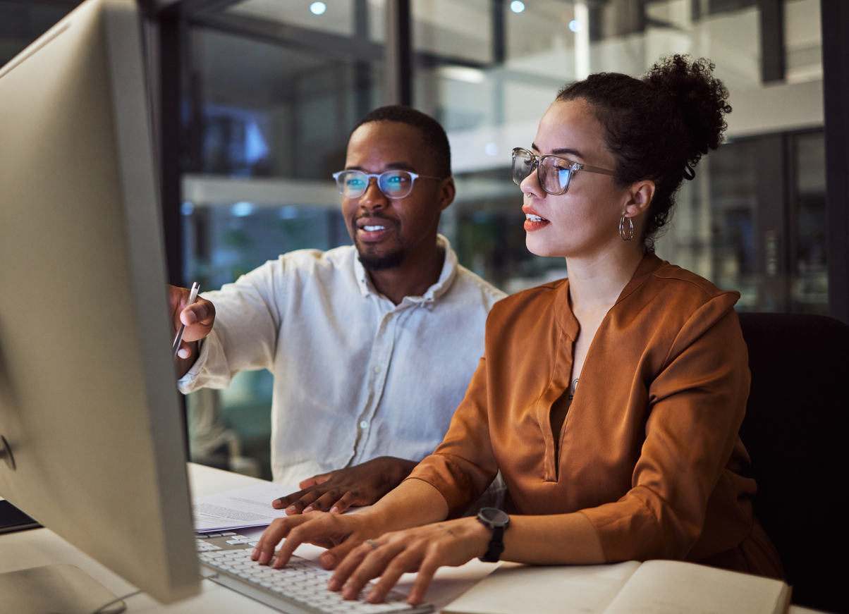 Man and woman looking at a computer screen together in the office in the evening