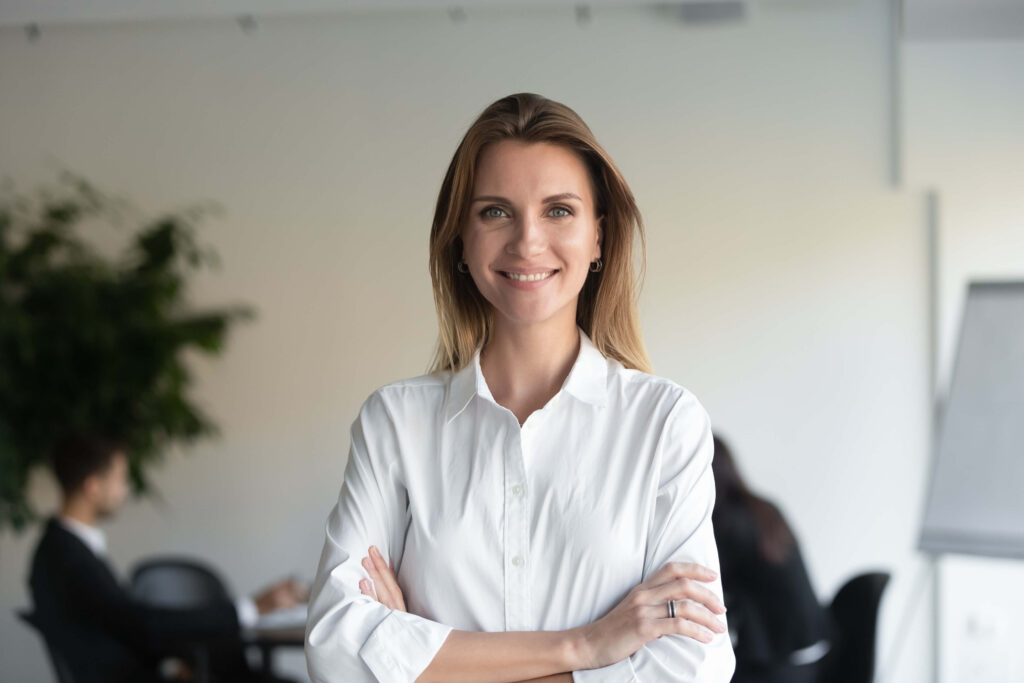 Laughing woman in a white shirt with folded arms in an office