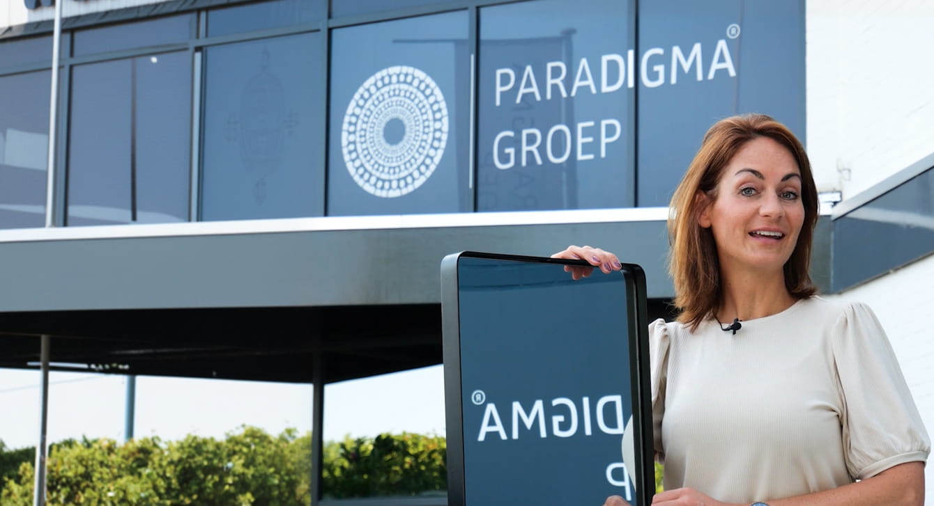 Woman presenting outside the paraDIGMA groep office, with the company logo on the facade