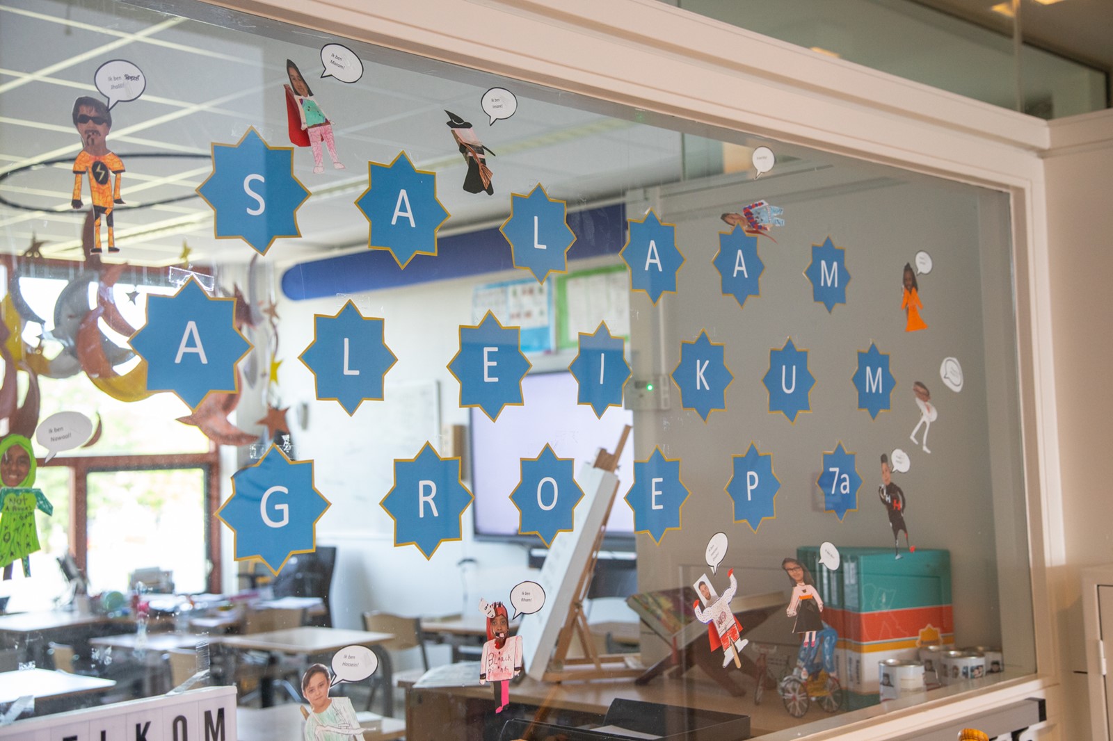 Classroom behind glass with blue stars spelling Salaam Aleikum groep 7a and paper figures