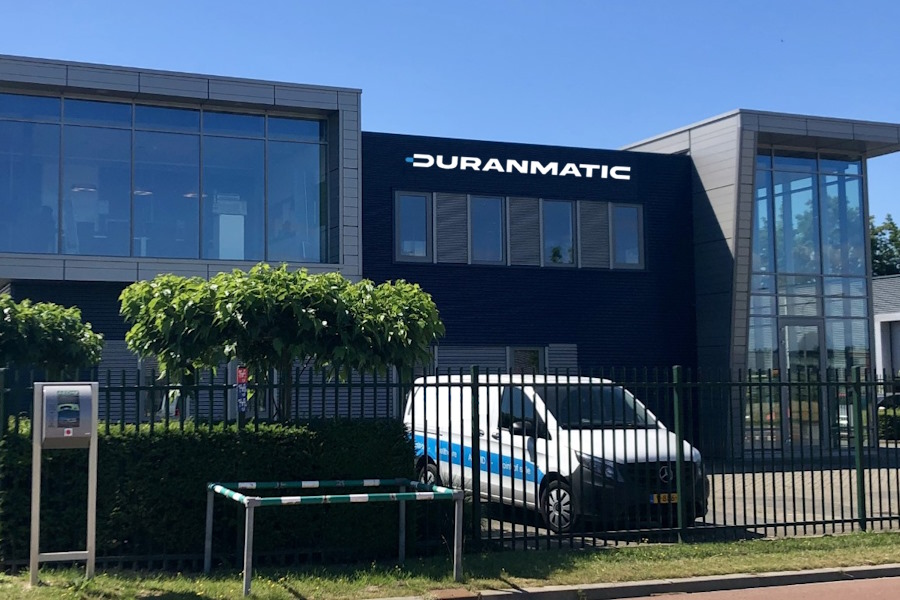 Kantoorgebouw van Duranmatic met een bedrijfsbusje voor het hek