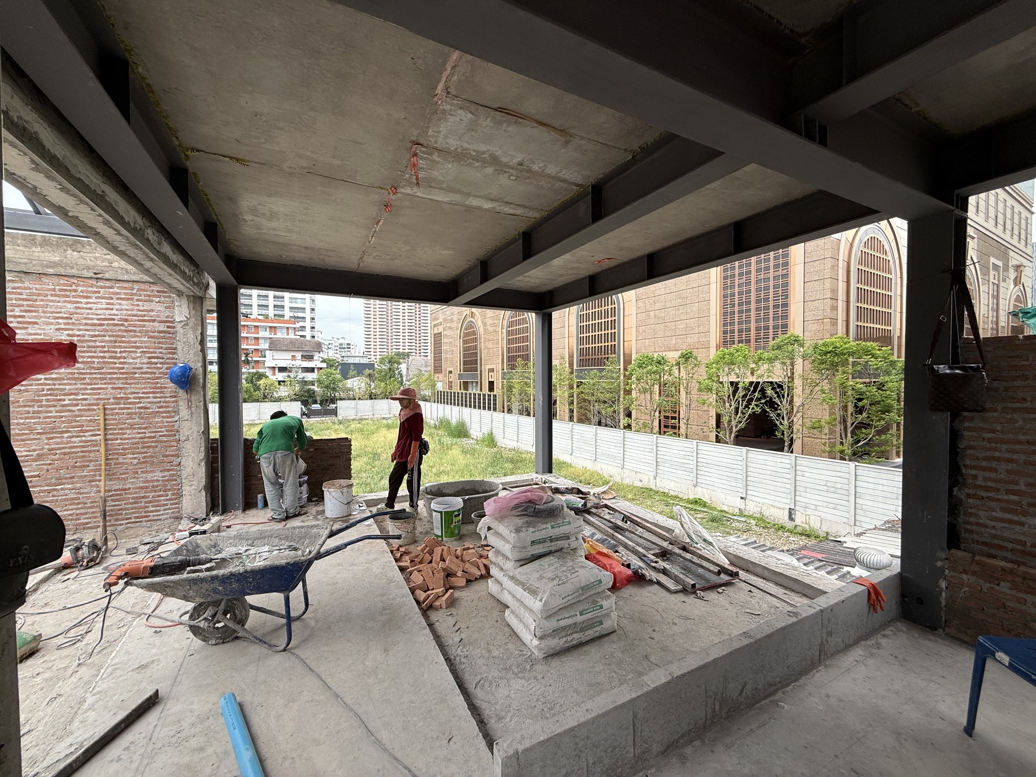 The same terrace under construction, bare steel and slab, workers and materials on site