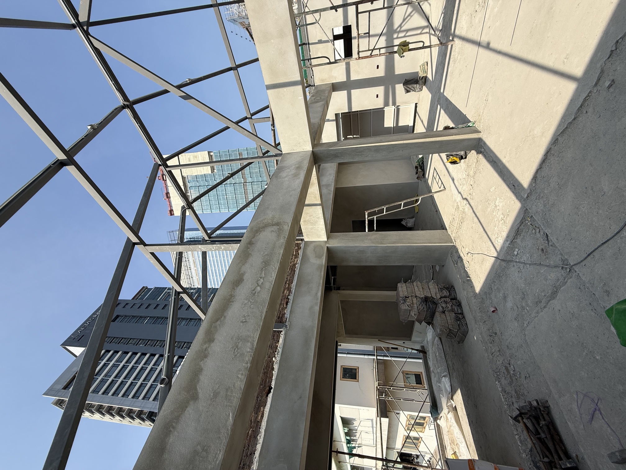 The same floor under construction, raw concrete beams and an open steel frame against the sky