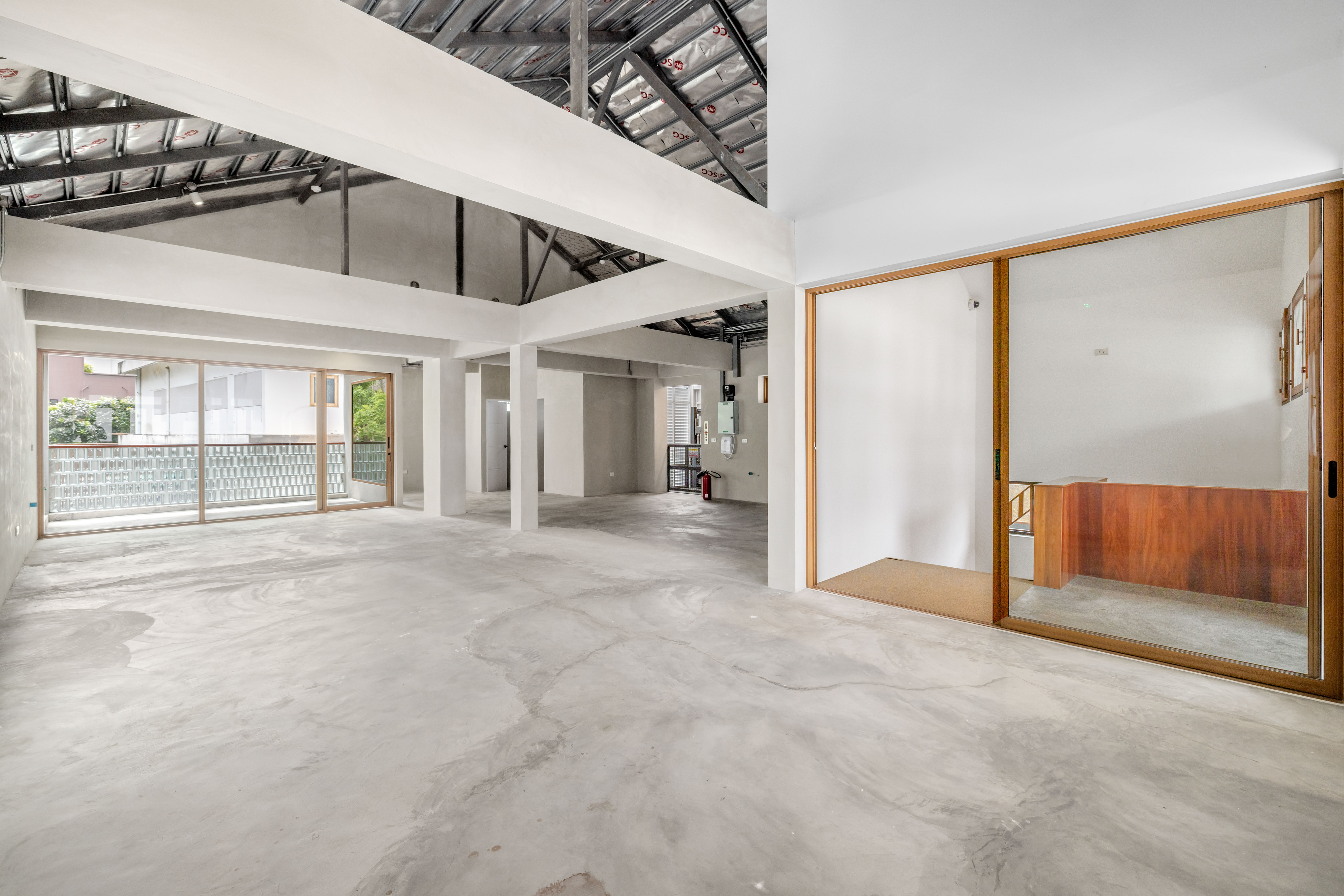 The upper floor today, a white-walled hall under exposed roof trusses with timber framed glazing
