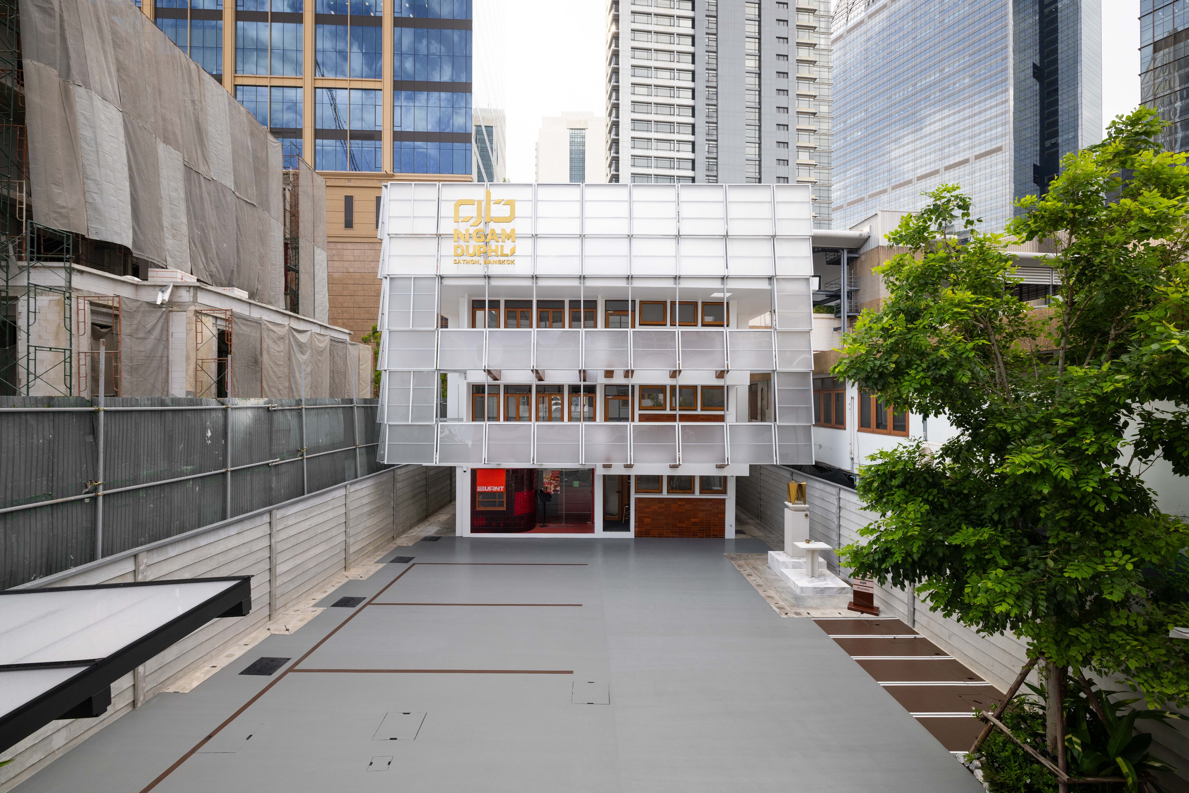 The restored facade today, translucent panels over timber windows, seen from the courtyard