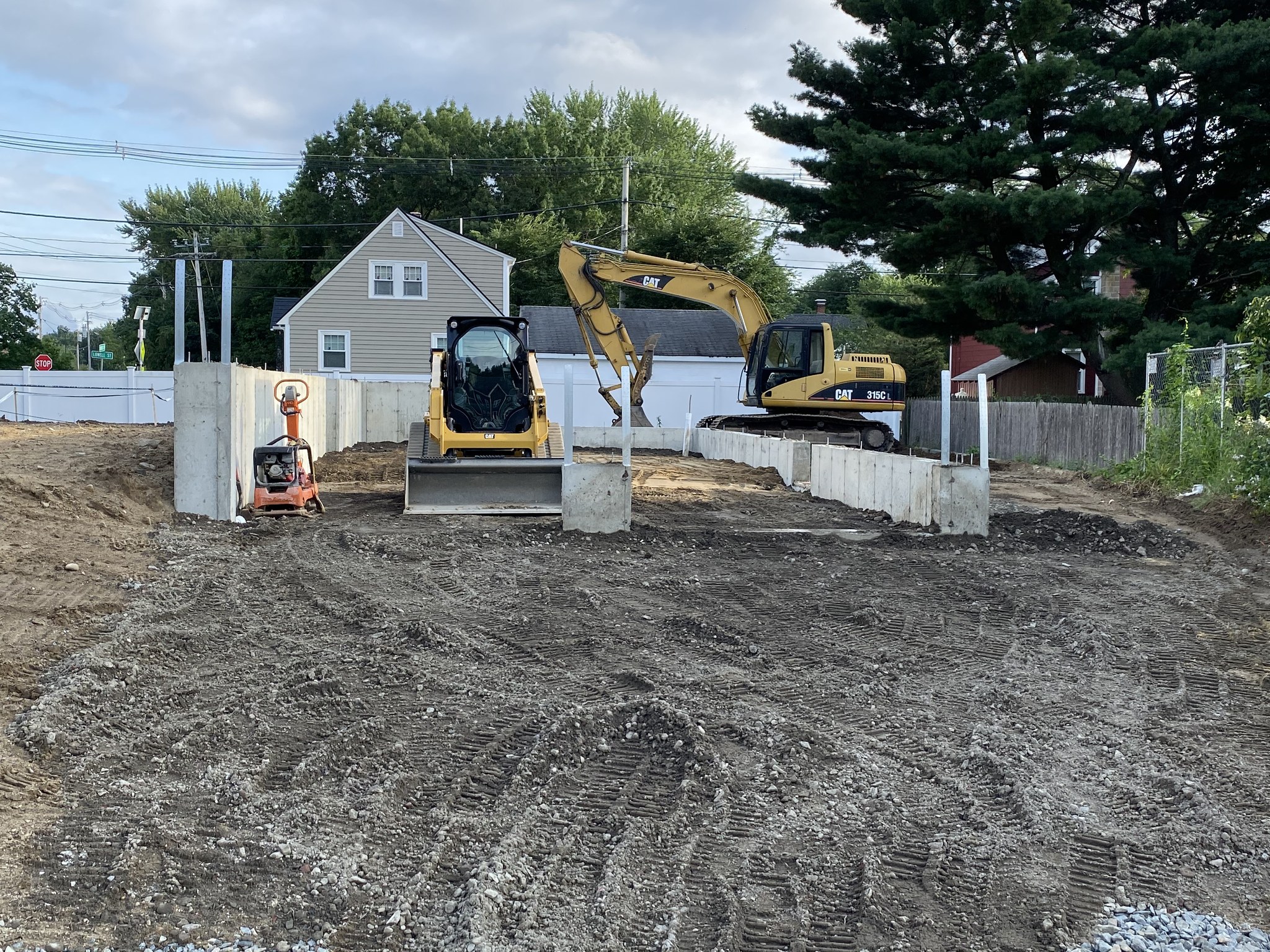 Excavator and skid steer grading a Wilmington build site after the foundation pour