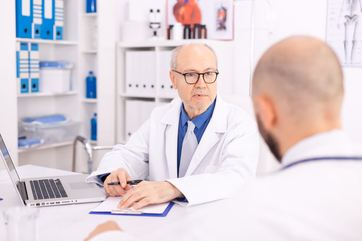 Two clinicians reviewing a case together, one explaining a decision to the other