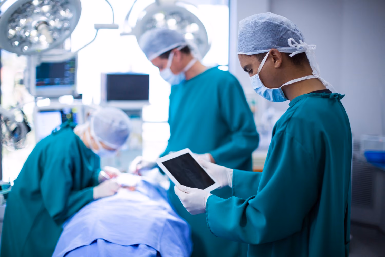 An anaesthetist checking a case record on a tablet in theatre before the first case