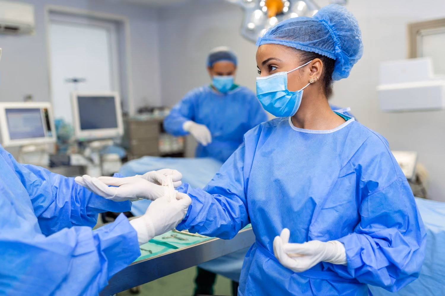 A nurse helping a surgeon into gloves as the team prepares for the first case of the list