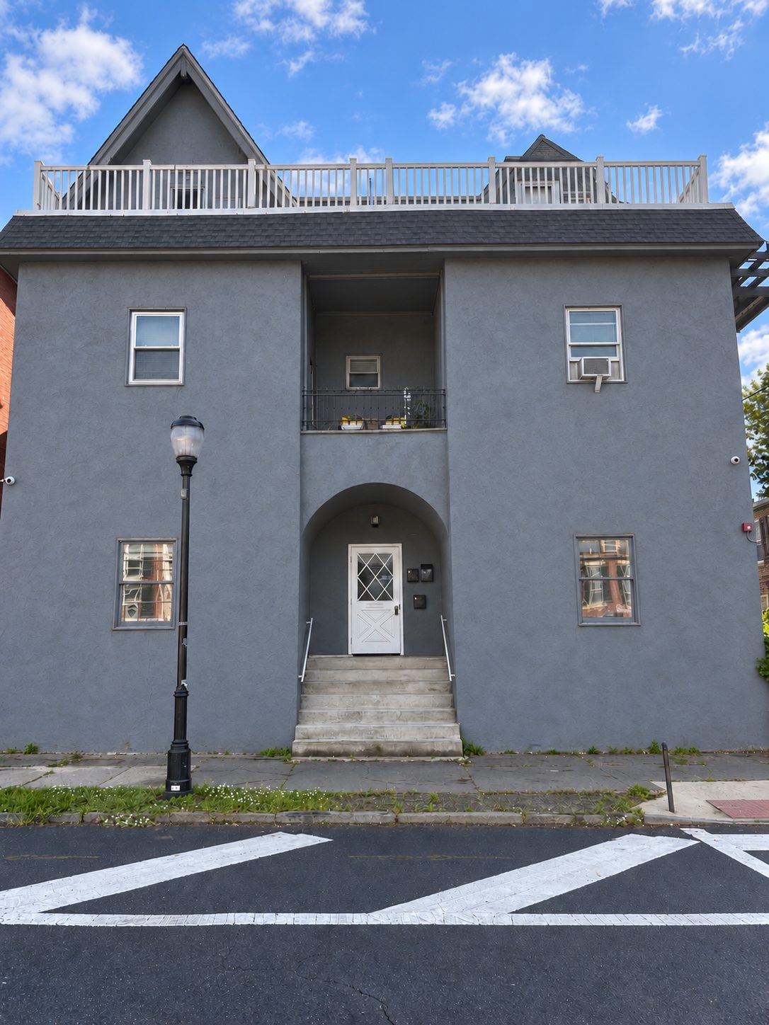 Gray stucco multifamily building with arched entry