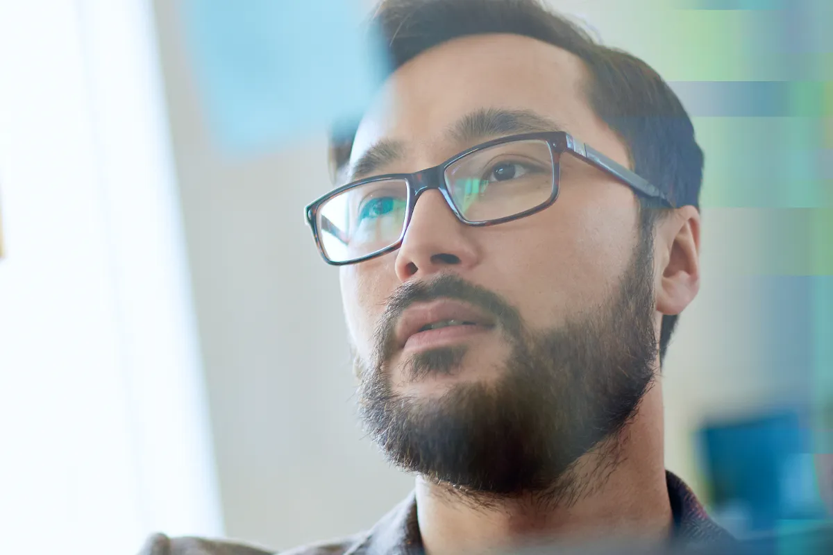 A close-up of a man in glasses looking off to the side thoughtfully