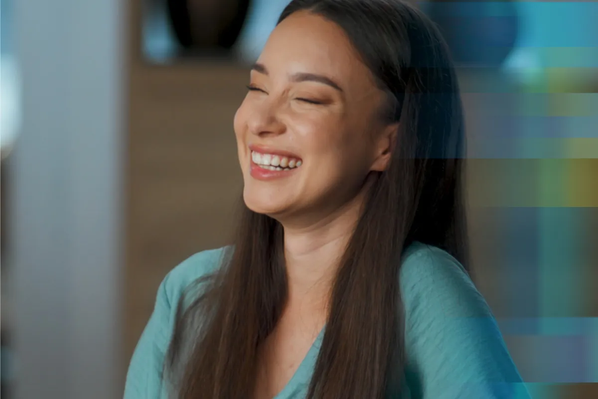 A woman laughing joyfully in a warmly lit room
