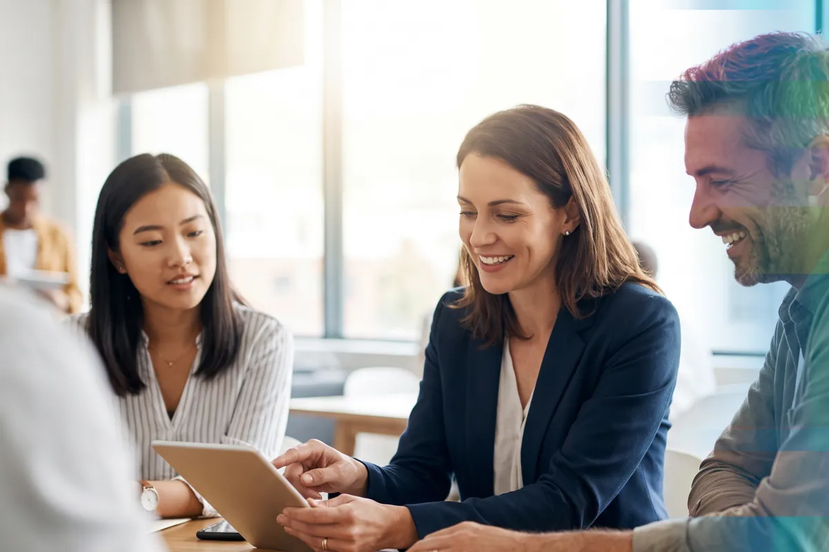 A businesswoman pointing to a tablet while two colleagues look on