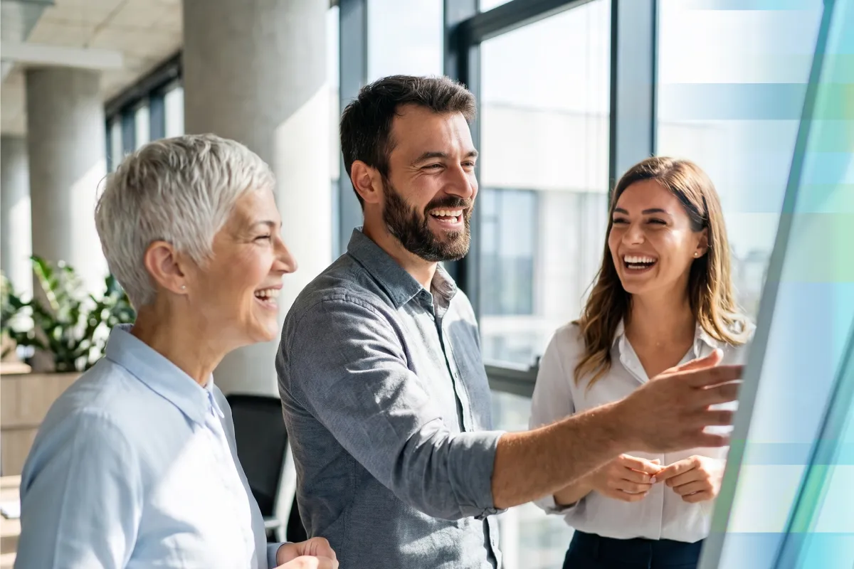 Three coworkers laughing together while looking at a presentation screen