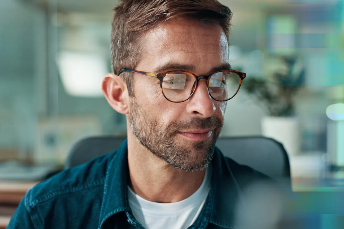 Close-up of a smiling bearded man wearing glasses, looking to the side