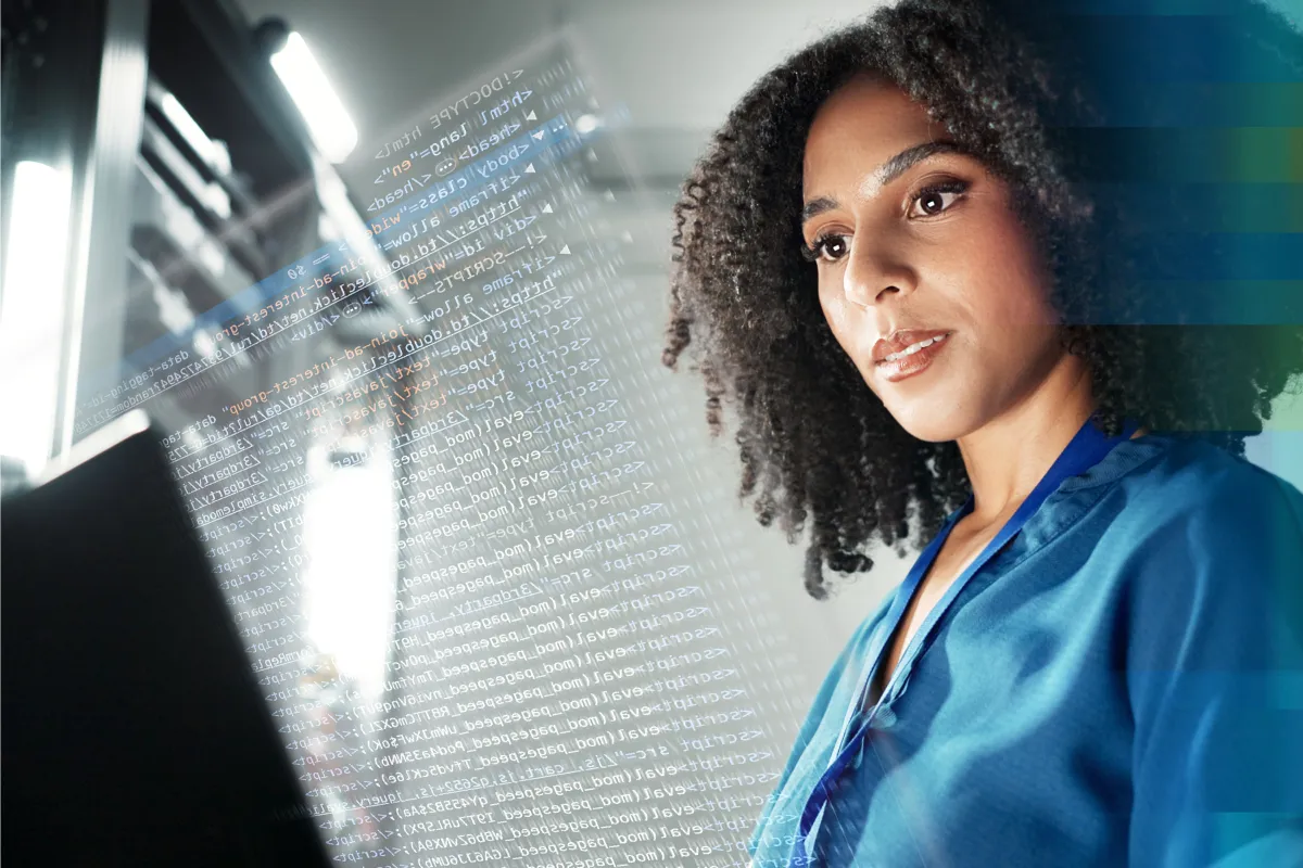 Woman in scrubs looking at a screen displaying lines of digital data