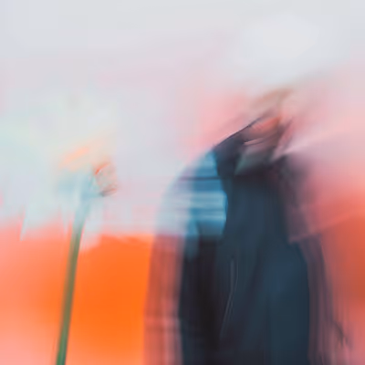 Abstract blurred photo of a person standing next to a streetlight with colorful background.