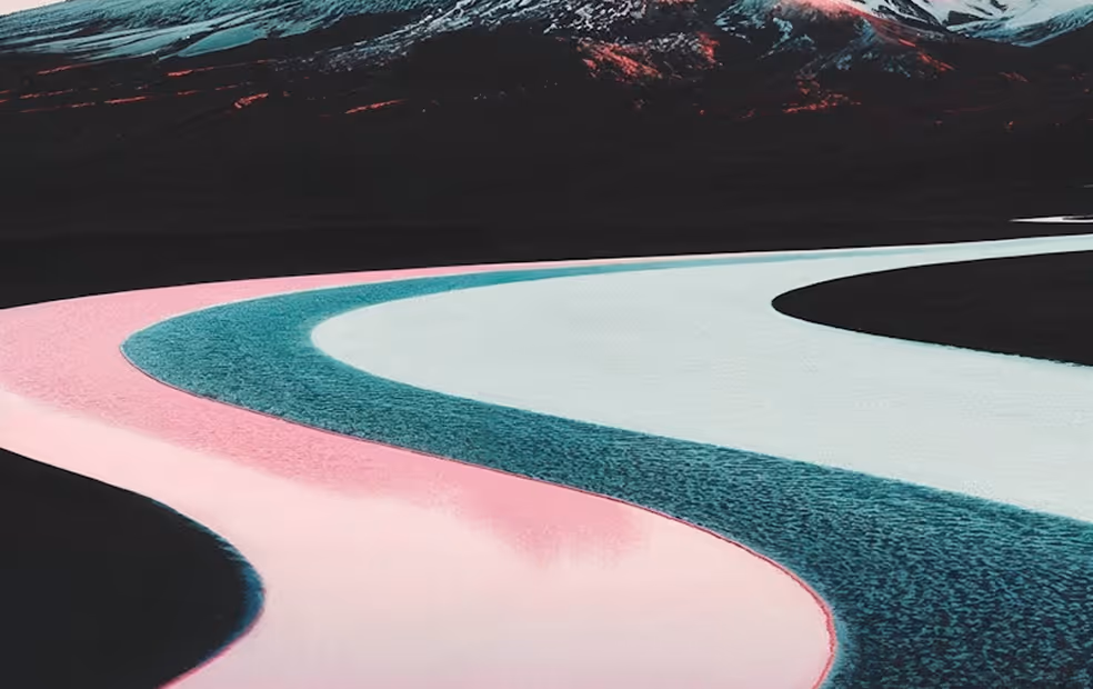 Curving river with pastel pink and teal waters flowing through dark landscape under a mountain.