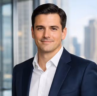 Smiling man in a navy suit and white shirt with a city skyline background through glass windows.