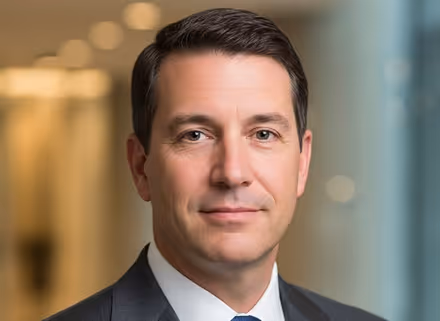 Portrait of a professional man in a suit with a blurred office background.