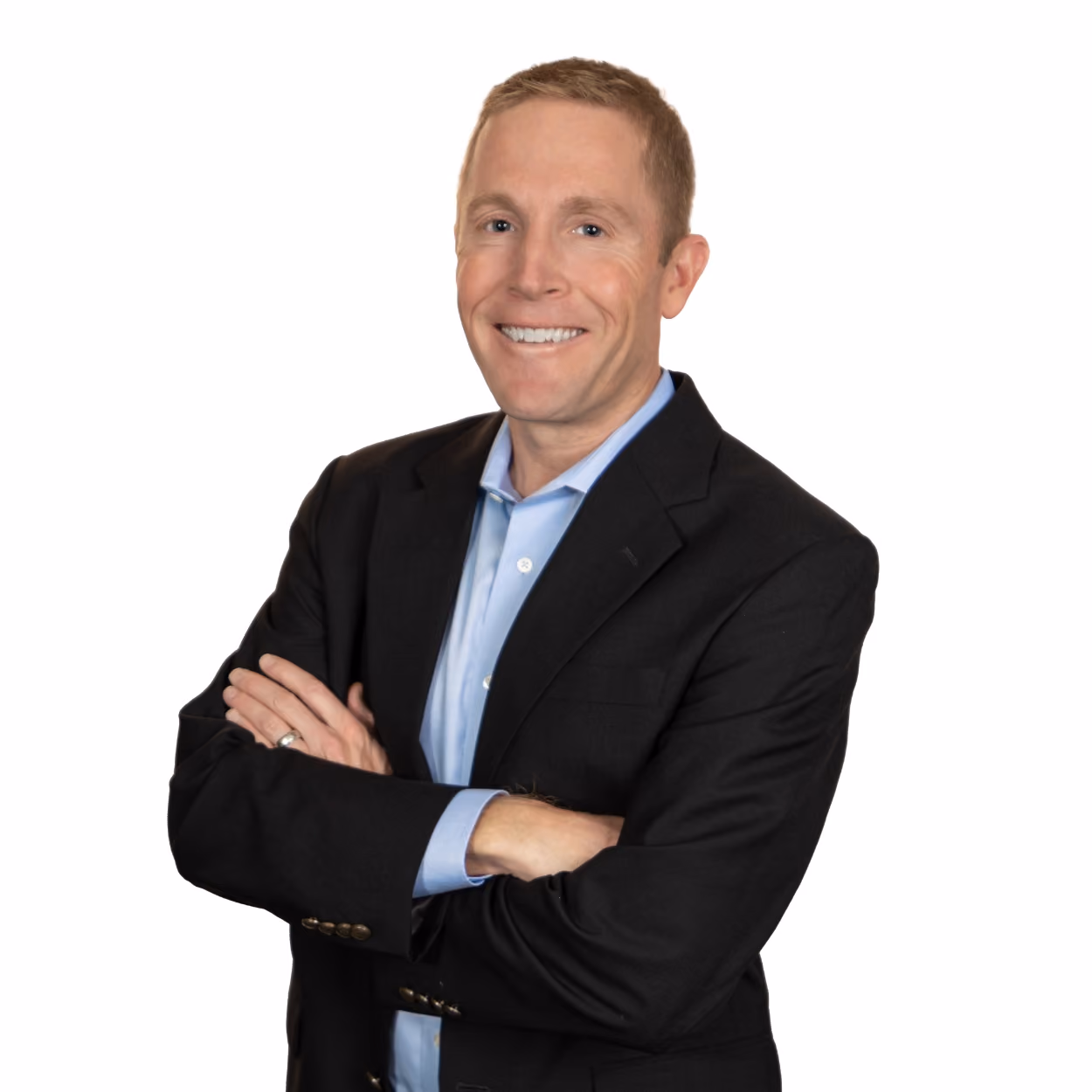 Smiling man in black blazer and light blue shirt with arms crossed against white background.