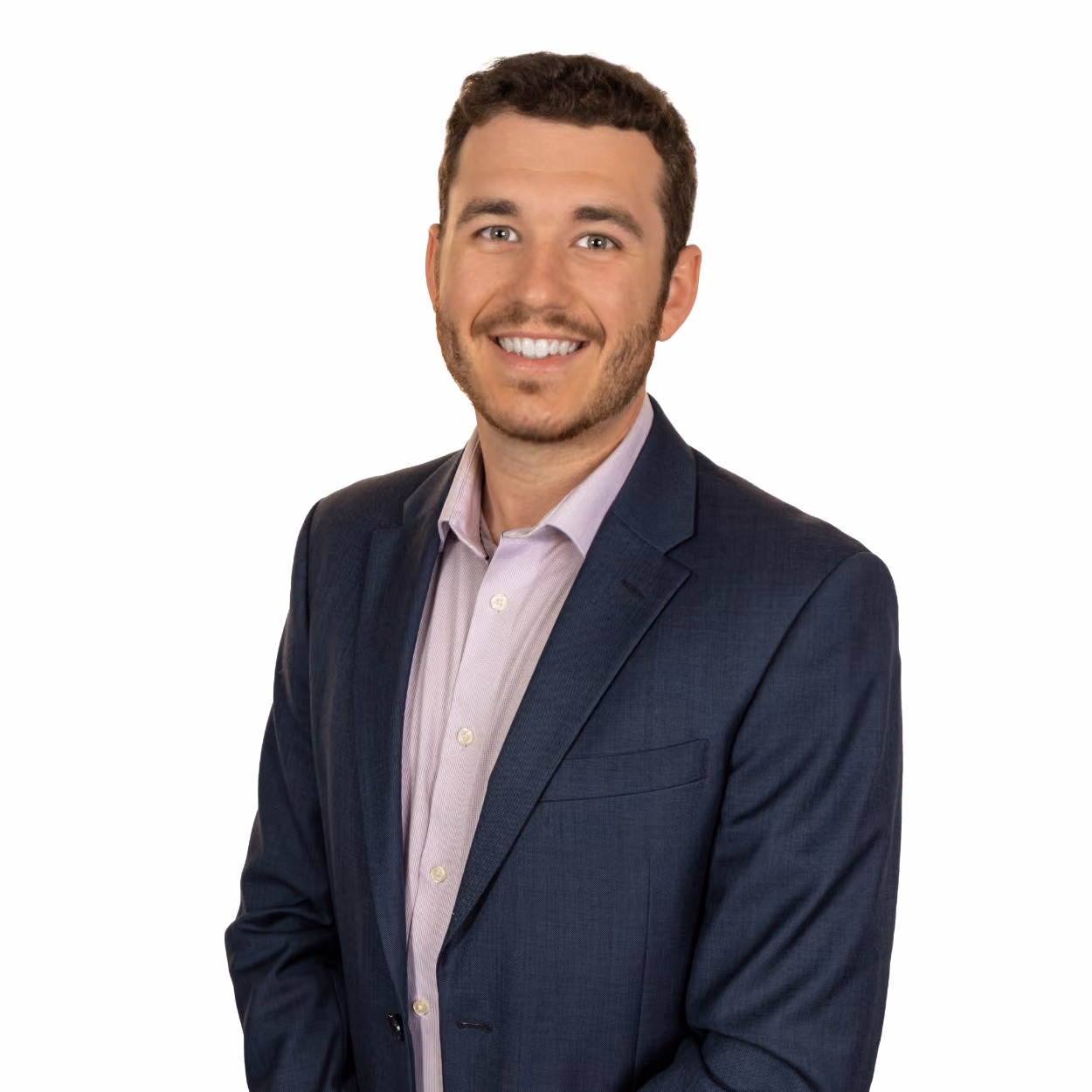 Smiling man with short curly hair wearing a navy blazer and light pink collared shirt.