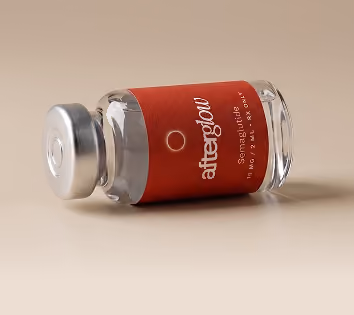 A small glass vial lying on its side with a silver cap and a red label that reads 'afterglow Seragmatides 11 ml 3.7 fl oz.'