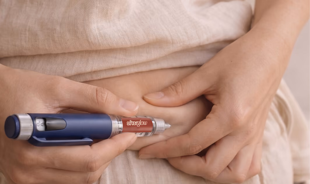 Close-up of person using an Afterglow branded lancet device to prick their abdominal skin for blood sampling or glucose testing.