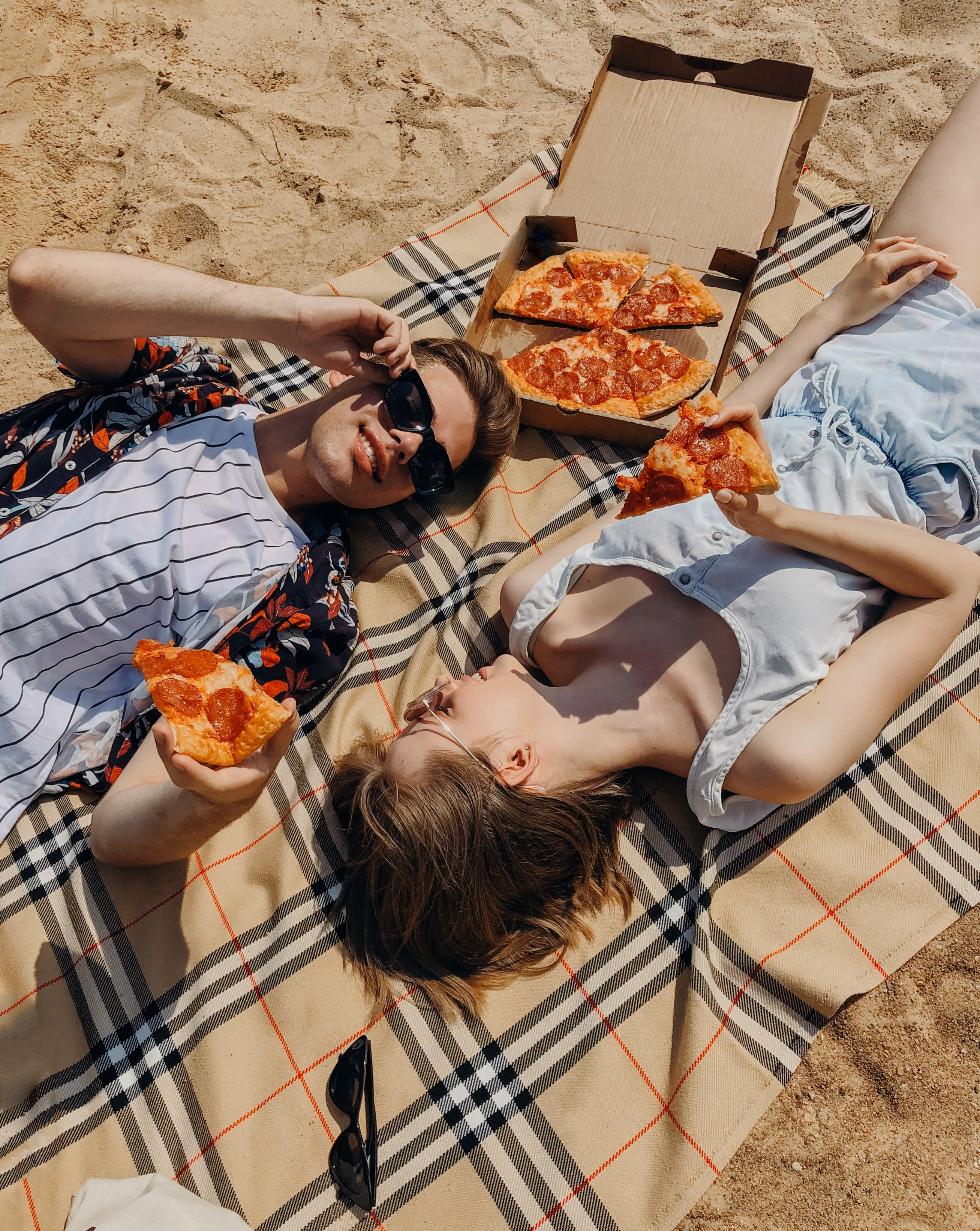 Man and woman laying on the beach eating pizza stock image